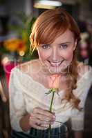 Portrait of female florist smelling a rose flower