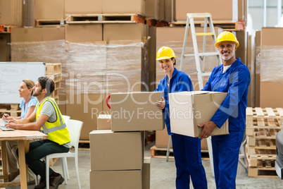 Portrait of delivery workers carrying cardboard box