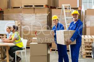 Portrait of delivery workers carrying cardboard box