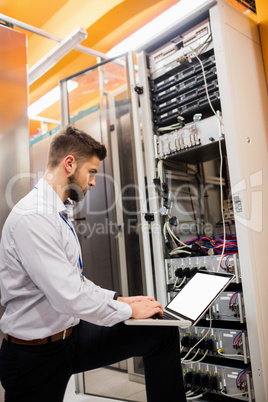 Technician using laptop while analyzing server