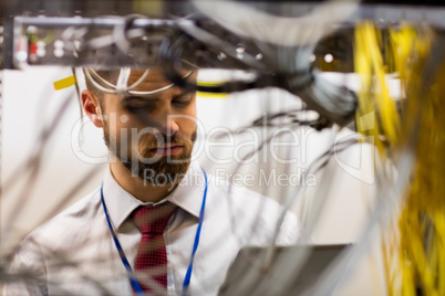 Technician using digital tablet while analyzing server