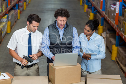 Warehouse workers and manager discussing with laptop