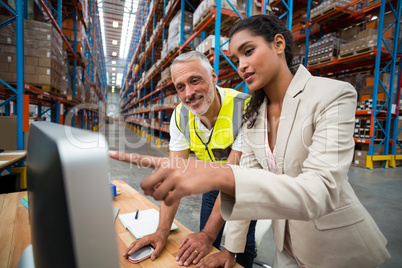 Warehouse manager and worker discussing with computer