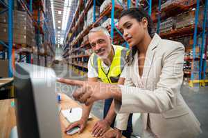 Warehouse manager and worker discussing with computer