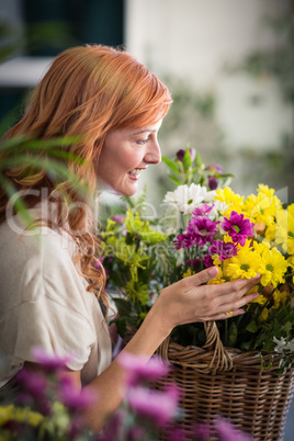 Happy female florist holding basket of flowers