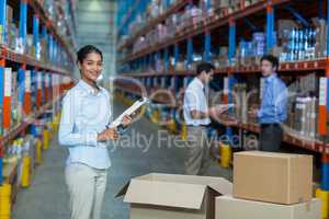 Portrait of female warehouse worker standing with clipboard