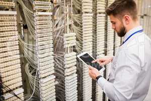 Technician using digital tablet while analyzing server
