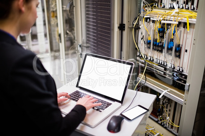 Technician using laptop while analyzing server