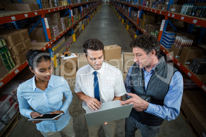 Warehouse workers and manager discussing with laptop