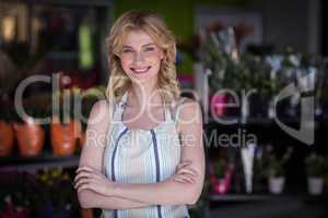 Happy female florist standing with arms crossed in flower shop