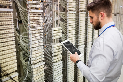 Technician using digital tablet while analyzing server Technician using digital tablet while analyzing server