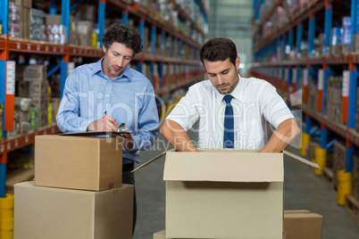 Two warehouse workers checking the boxes