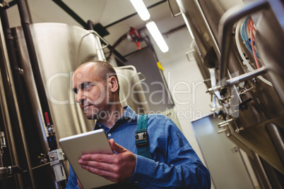 Manufacturer with digital tablet examining machinery