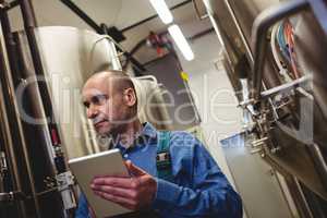 Manufacturer with digital tablet examining machinery