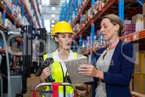 Warehouse manager with interacting female worker over digital tablet