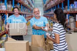 Three volunteers packing eatables in cardboard box