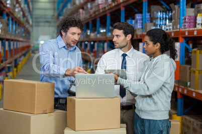 Warehouse manager and worker discussing with laptop