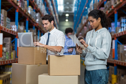 Warehouse worker working on laptop and digital tablet