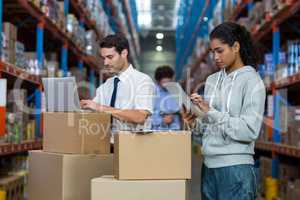 Warehouse worker working on laptop and digital tablet