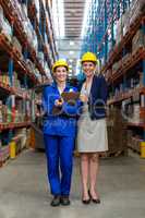 Warehouse manager and worker standing together in warehouse