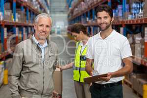 Warehouse manager and male worker smiling while working