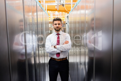 Technician standing with arms crossed in a server room