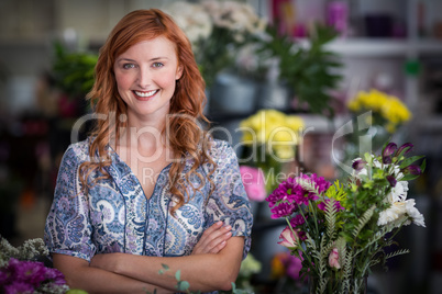 Happy female florist standing with arms crossed in flower shop