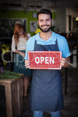 Male florist holding open signboard