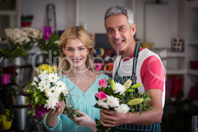 Smiling florists holding bunch of flowers in flower shop