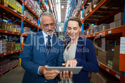 Warehouse manager and client discussing over digital tablet