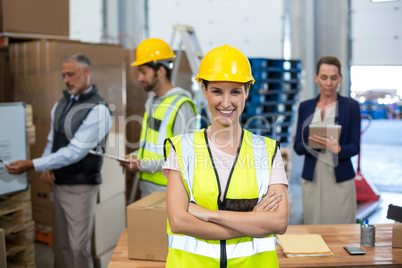 Portrait of female warehouse worker standing with arms crossed