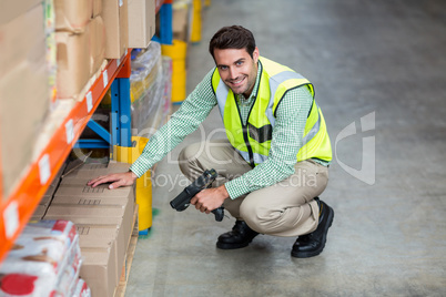 Portrait of smiling warehouse worker scanning box