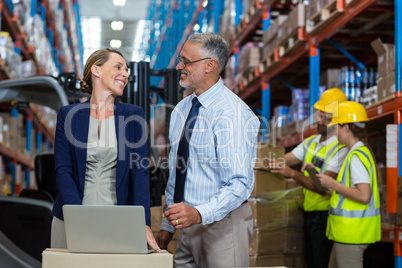 Warehouse manager and client interacting over laptop