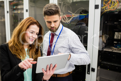 Technicians using digital tablet while analyzing server