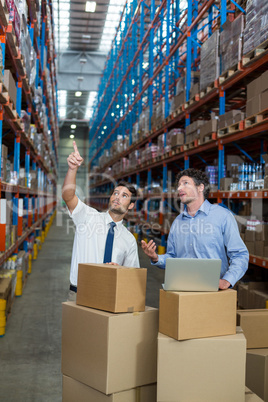 Warehouse workers discussing with laptop