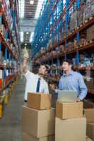 Warehouse workers discussing with laptop