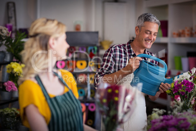 Smiling florist watering flowers