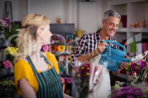 Smiling florist watering flowers