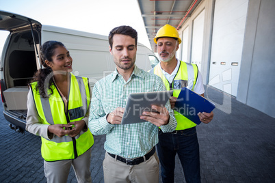 Manager and warehouse workers discussing with digital tablet