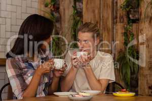 Female friends interacting with each other while having coffee