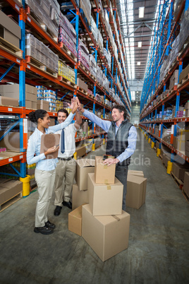 Happy warehouse workers giving high five