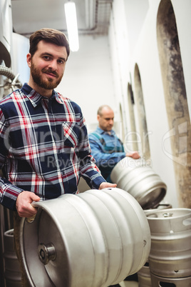 Confident owner carrying kegs at brewery