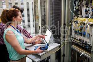 Technicians using laptop while analyzing server