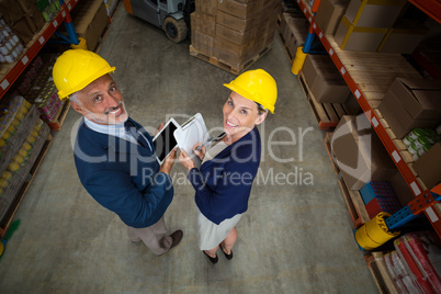 Warehouse manager and client holding digital tablet and clipboard