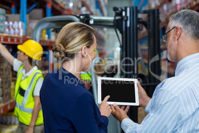 Warehouse manager and client discussing over digital tablet