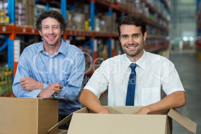 Portrait of two warehouse workers standing together with boxes