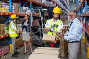 Warehouse manager holding digital tablet while male worker scanning barcode