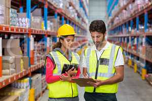 Warehouse workers discussing with clipboard while working