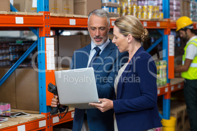 Warehouse manager and client using laptop