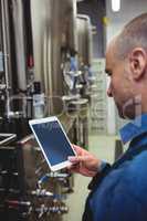 Male owner using digital tablet at brewery